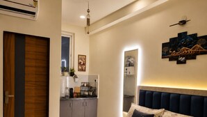 Een slaapkamer met een bed, nachtkastje, luchtverfrisser aan de muur, plafondlamp en kunstwerk aan de wand.