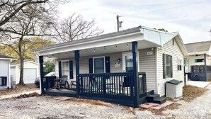 Une maison de plain-pied avec un porche couvert, une porte d’entrée et un petit garage.