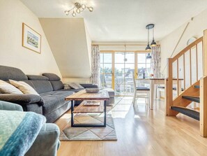 Ein modernes Wohnzimmer mit einer Couch, einem Couchtisch und Blick auf die Stadt durch große Fenster.