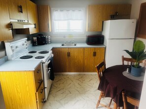 Una cocina con armarios de madera, una estufa blanca, un microondas y un lavamanos.