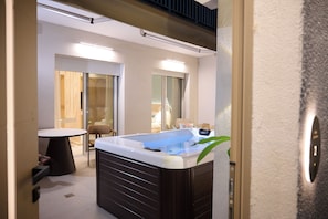 Un baño moderno con una bañera, una mesita pequeña y una silla.