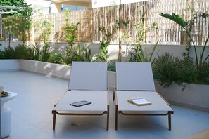 Dos sillones con libros, una mesita y una silla blanca con una taza.