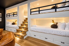 Ein modernes Schlafzimmer mit Etagenbett, einer Holztreppe und eingebauten Stauraumschubladen.