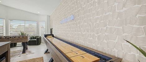 Een biljarttafel met een houten tafelblad en een gestructureerde muur ernaast.