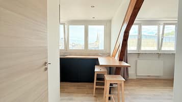 A modern kitchen with a wooden countertop, a black cabinet, and a window overlooking a cityscape.