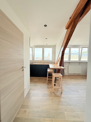 A modern kitchen with a wooden countertop, a black cabinet, and a window overlooking a cityscape.