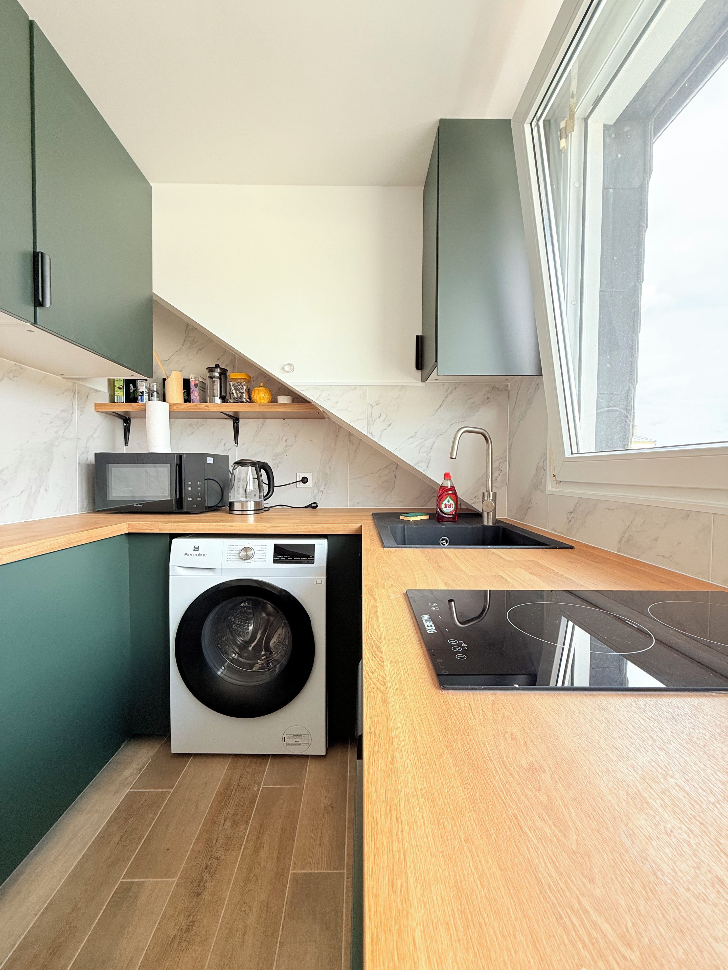 A compact kitchen with a built-in washing machine, a microwave, and a sink.