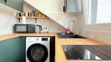 A compact kitchen with a built-in washing machine, a microwave, and a sink.
