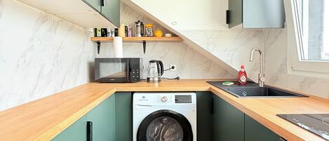 A compact kitchen with a built-in washer, a sink, and a window.