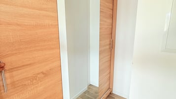 A room with a sliding wooden door, a white wall, and a tiled floor.