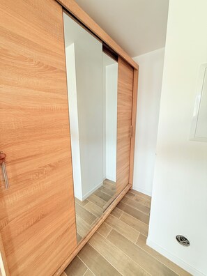 A room with a sliding wooden door, a white wall, and a tiled floor. - Contemporary Apartment Bright & Equipped (Esch-sur-Alzette)