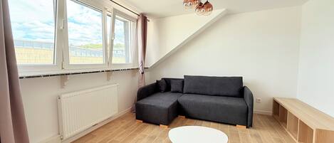 A modern living room with a sectional sofa, a round coffee table, and a large window with curtains.