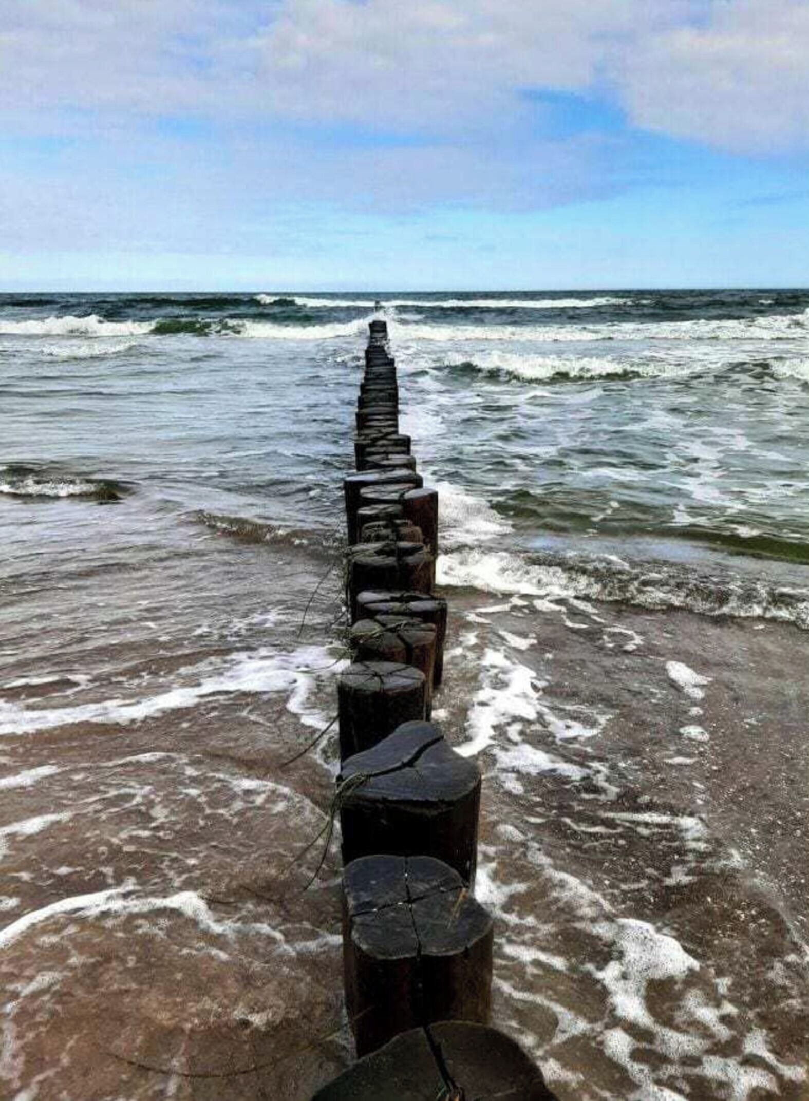 Ein hölzerner Wellenbrecher, der sich ins Meer erstreckt.