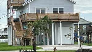 Um edifício residencial de dois andares com uma varanda, um pequeno alpendre e uma bandeira americana visível.