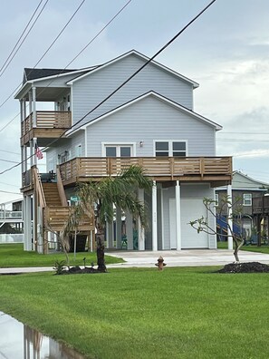 A multi-story residential building with a balcony, a small garden, and a visible American flag. - Beautiful Beach Home on the West End of Galveston with Beach across the street (Galveston)
