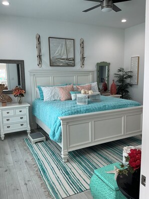 A bedroom with a bed, bedside tables, a mirror, and a ceiling fan. - Beautiful Beach Home on the West End of Galveston with Beach across the street (Galveston)