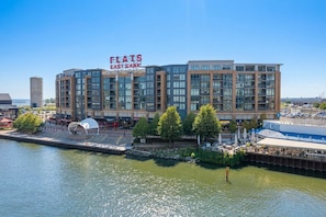 Ein Hotel am Wasser mit modernem architektonischem Design, mit einem markanten Schild für Flats East Bank, einem Anlegesteg und einem Restaurant namens Lake House.