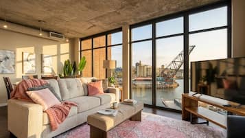 A modern living room with a large window, a sofa, a coffee table, and a TV.