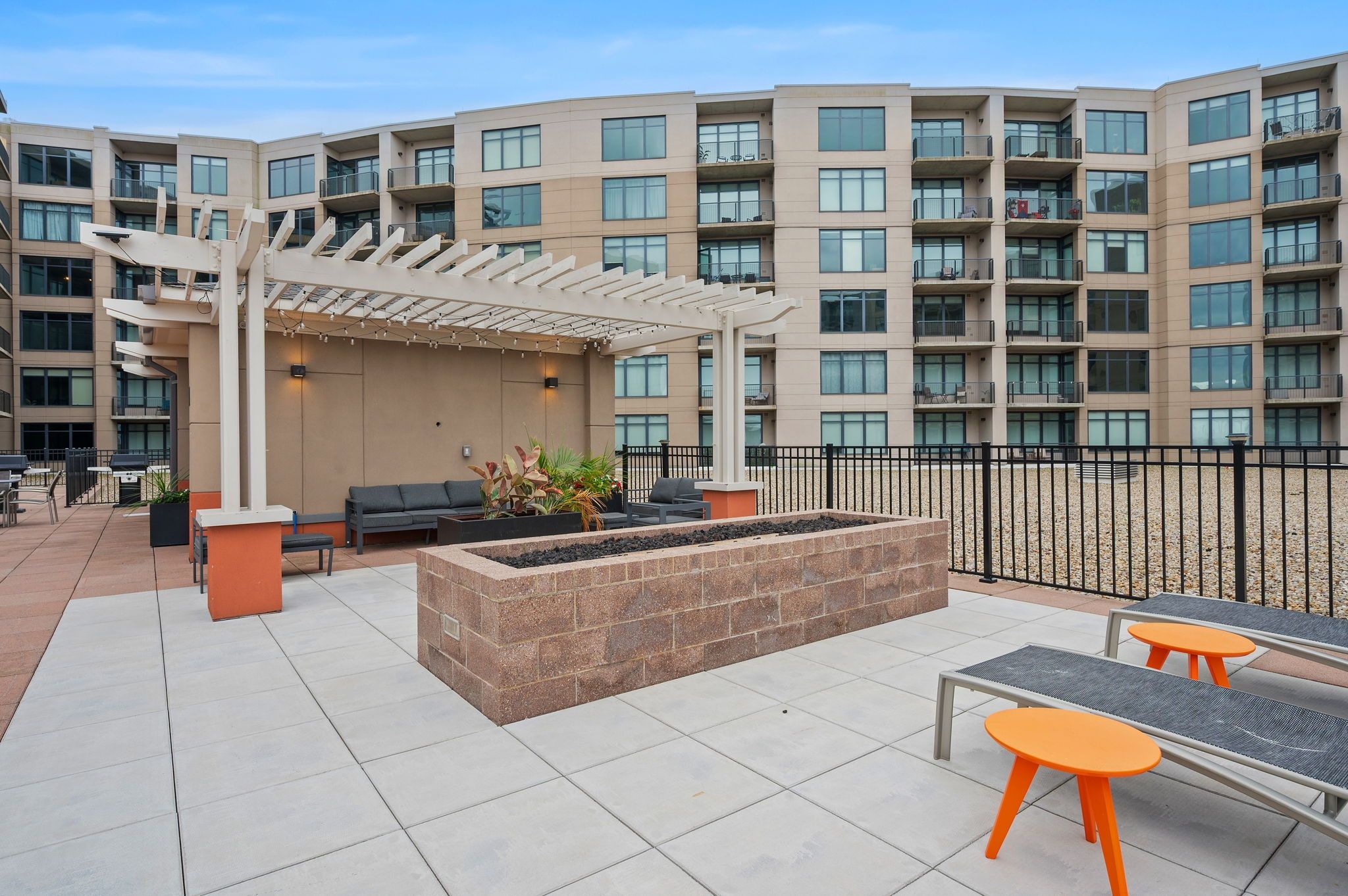 A rooftop patio with outdoor seating, a fire pit, and a pergola.