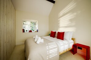 Une chambre à coucher avec un lit, une fenêtre, une table de chevet et une commode rouge.