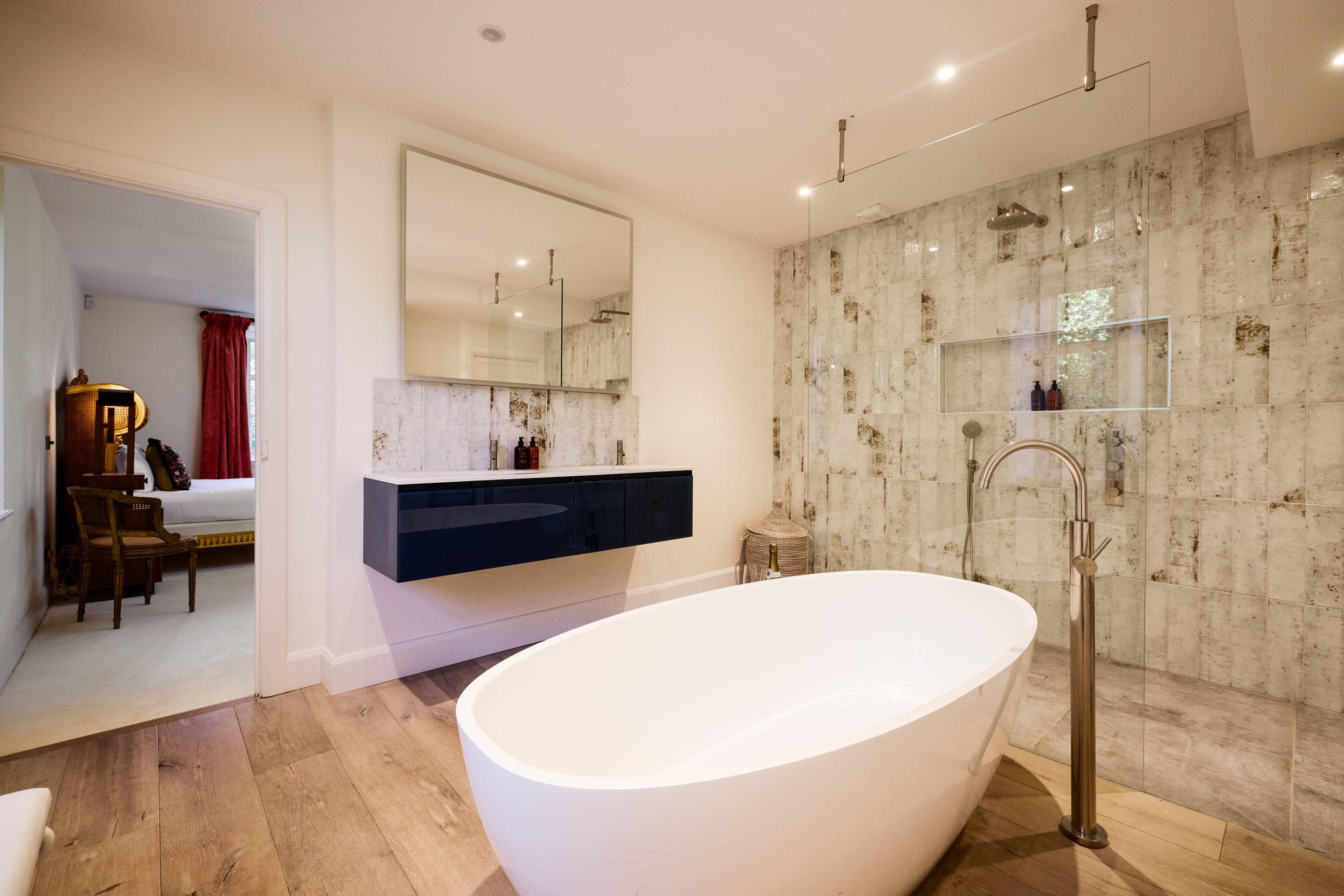 Un baño moderno con una bañera independiente, un espejo grande y un revestimiento de mármol.