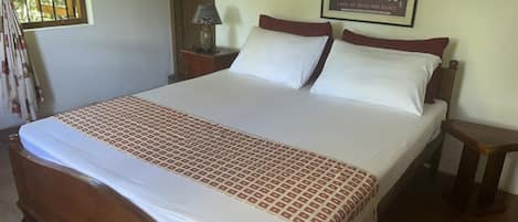 Una cama grande con colcha estampada, dos almohadas y cabecera de madera.
