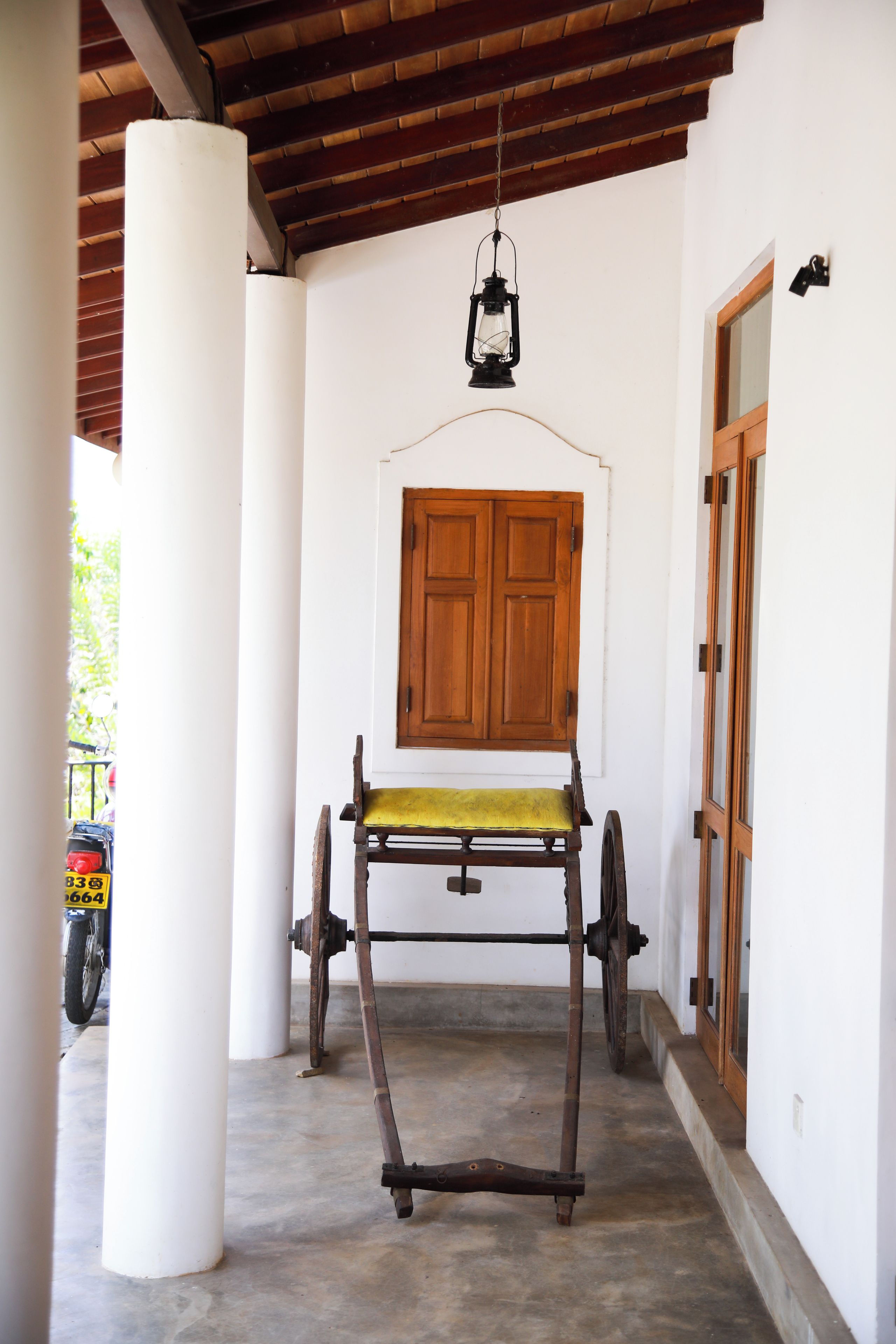 A covered porch with a wooden bench, a hanging lantern, and a wooden door.
