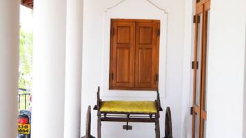 A covered porch with a wooden bench, a hanging lantern, and a wooden door.