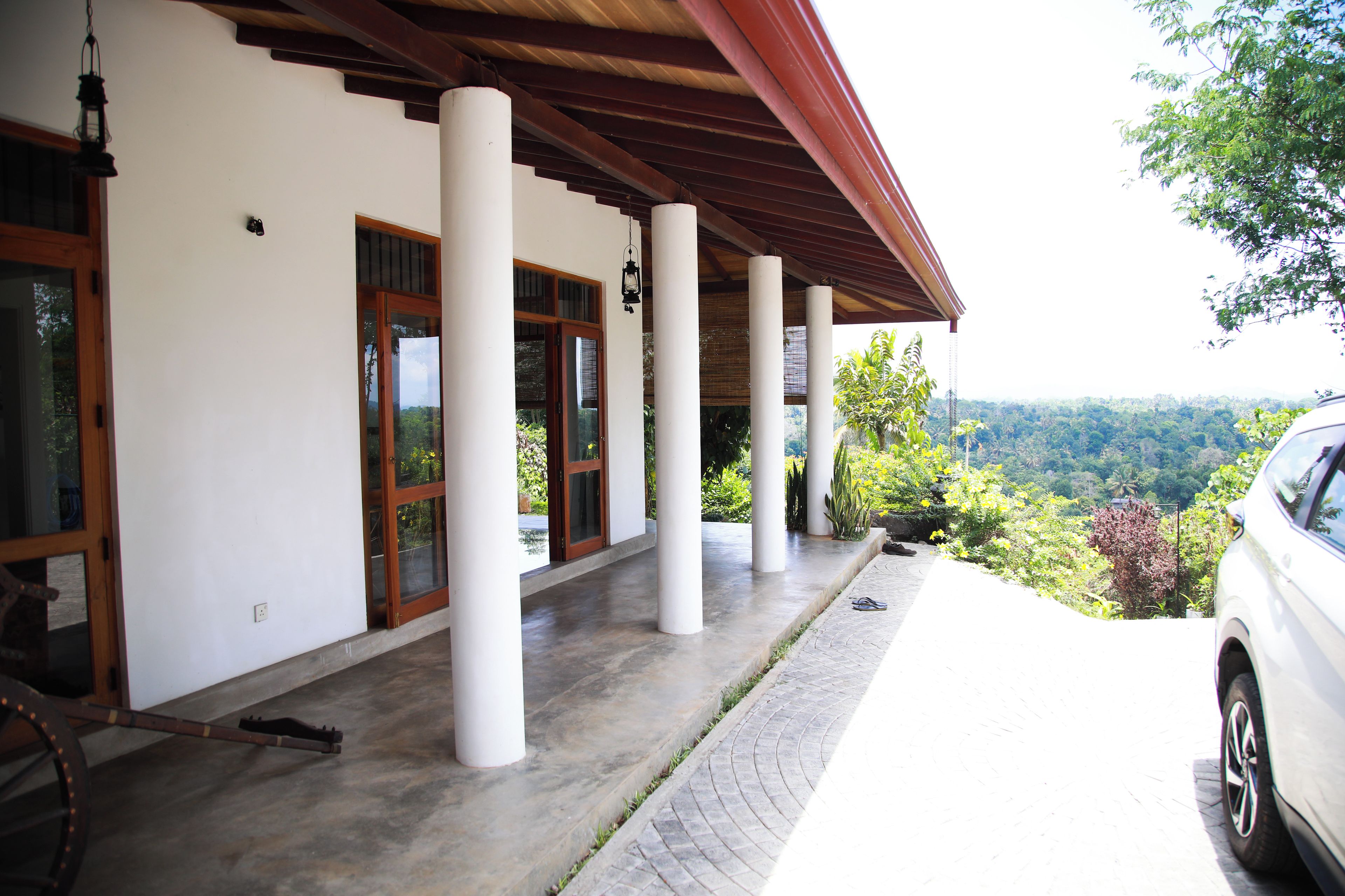 A covered outdoor area with columns, a car, and a view of a mountainous landscape.