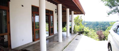 A covered outdoor area with columns, a car, and a view of a mountainous landscape.