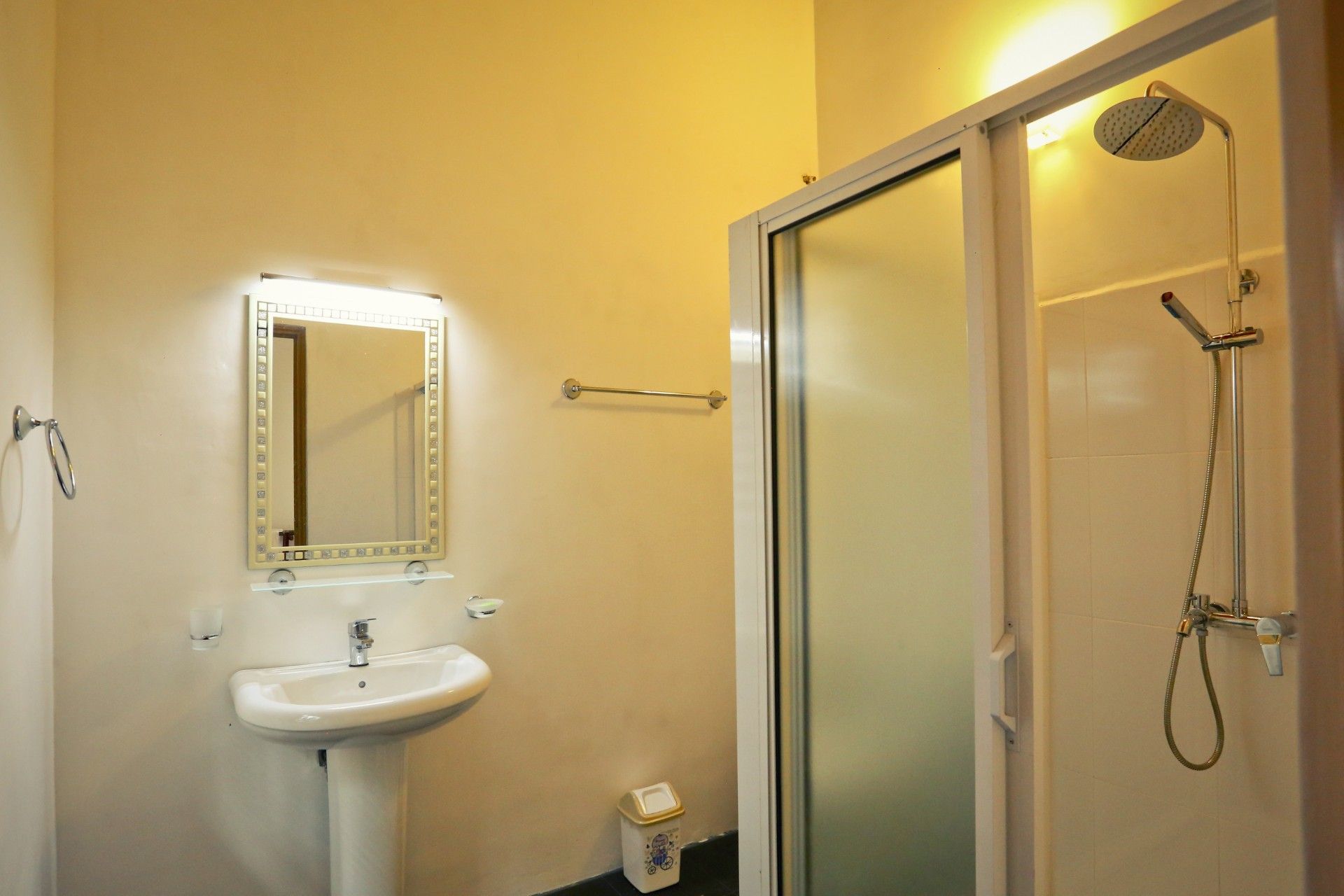 A bathroom with a sink, mirror, towel rack, and a shower with a handheld showerhead.