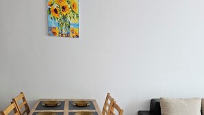 A dining area with a wooden table and chairs, a painting on the wall, and a sofa in the background. - Chateau apartment (Aheloy)