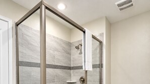 A modern bathroom with a glass-enclosed shower, a toilet, and a trash bin. - Spacious 9-bedroom house in fantastic Four Corners with AC (Four Corners)