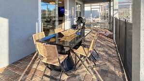 An outdoor patio with a glass-top table, wicker chairs, and a ceiling fan. - Spacious 9-bedroom house in fantastic Four Corners with AC (Four Corners)