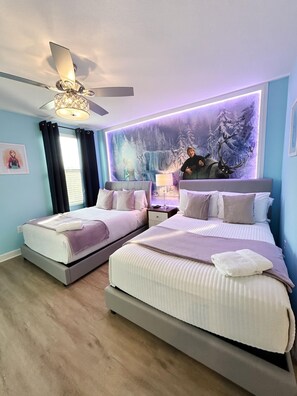 Quarto com duas camas, ventoinha no teto, painel decorativo na parede e janela com cortinas.
