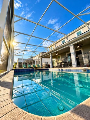 Piscina interna com paredes de vidro transparente, deck revestido de azulejos e ventilador de teto.