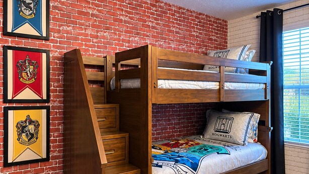 A bunk bed with a wooden ladder and drawers, a brick wall, and framed emblems on the wall. - Spacious 9-bedroom house in fantastic Four Corners with AC (Four Corners)