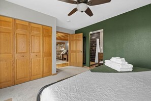 A bedroom with a large bed, wooden wardrobe, and a green accent wall.