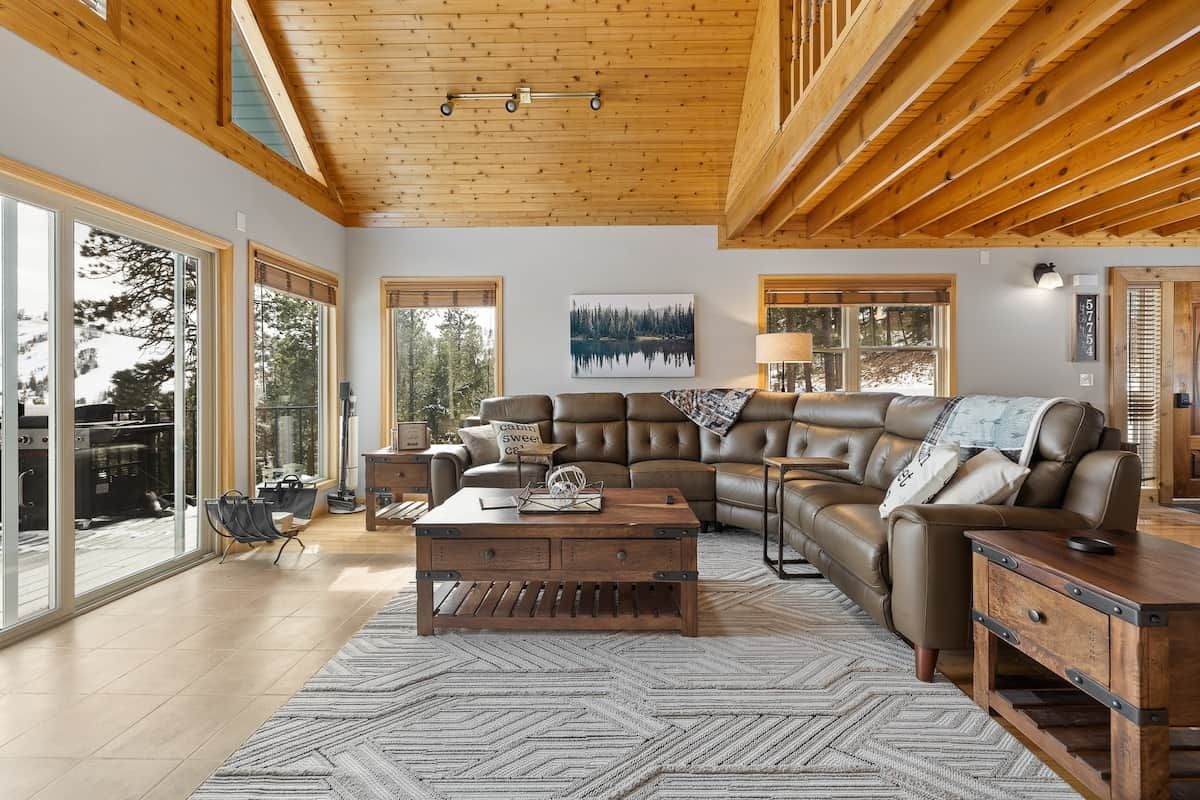 A spacious living room with a large sectional sofa, a wooden coffee table, and a herringbone-patterned rug.