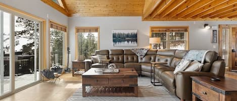 A spacious living room with a large sectional sofa, a wooden coffee table, and a herringbone-patterned rug.