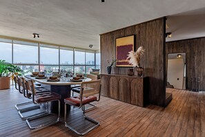 Eine moderne Küche mit einer Holzinsel, einem Essbereich mit Stühlen und einem großen Fenster mit Blick auf die Stadt.