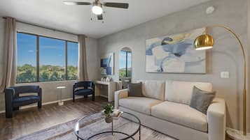 Una sala de estar moderna con un sofá, sillones, una mesa de centro, una lámpara de pie y un ventilador de techo.
