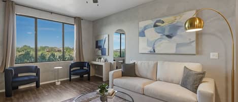 Una sala de estar moderna con un sofá, sillones, una mesa de centro, una lámpara de pie y un ventilador de techo.