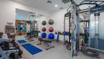 A gym with weightlifting equipment, exercise balls, and a squat rack.