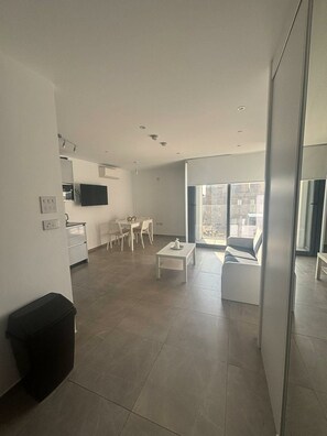 A modern living space with a dining area, a sofa, and a television. - Short Stay Experts A1 - E1 Studio floor 8 (Gibraltar)