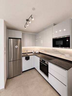 A modern kitchen with stainless steel appliances, white cabinetry, and a marble backsplash. - Short Stay Experts A1 - E1 Studio floor 8 (Gibraltar)