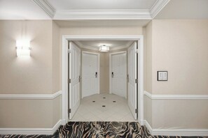A hallway with two doors, a light fixture, and a carpeted floor. - Luxury Strip View Condo - Balcony - MGM Signature (Las Vegas)
