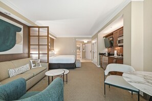 A hotel room with a bed, a sofa, a dining table, and a kitchen area. - Luxury Strip View Condo - Balcony - MGM Signature (Las Vegas)