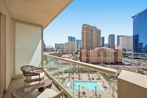 Ein Balkon mit Korbmöbeln, der einen Swimmingpool und eine Stadtansicht bietet.