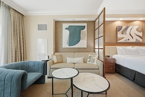 Ein Hotelzimmer mit einer Couch, einem Bett, einem kleinen Tisch und Bildern an den Wänden.